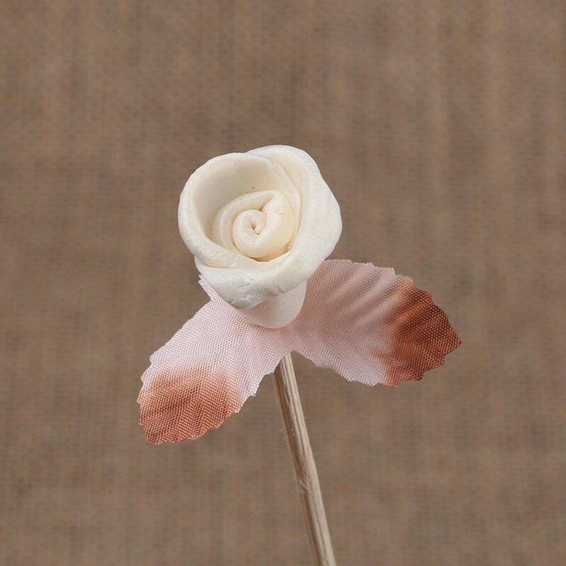 Close-up detail of miniature paper rose bud, highlighting realistic curling petals and flexible vine for reed diffusers.