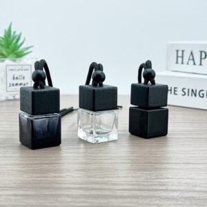 The Solid Black square bottle with black wood lid, hanging elegantly from a car's air vent.
