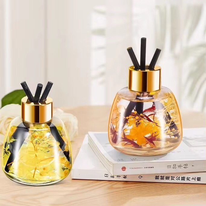 The 100ml and 250ml apple-shaped glass bottles side by side, both with gold lids, showing clear size difference.