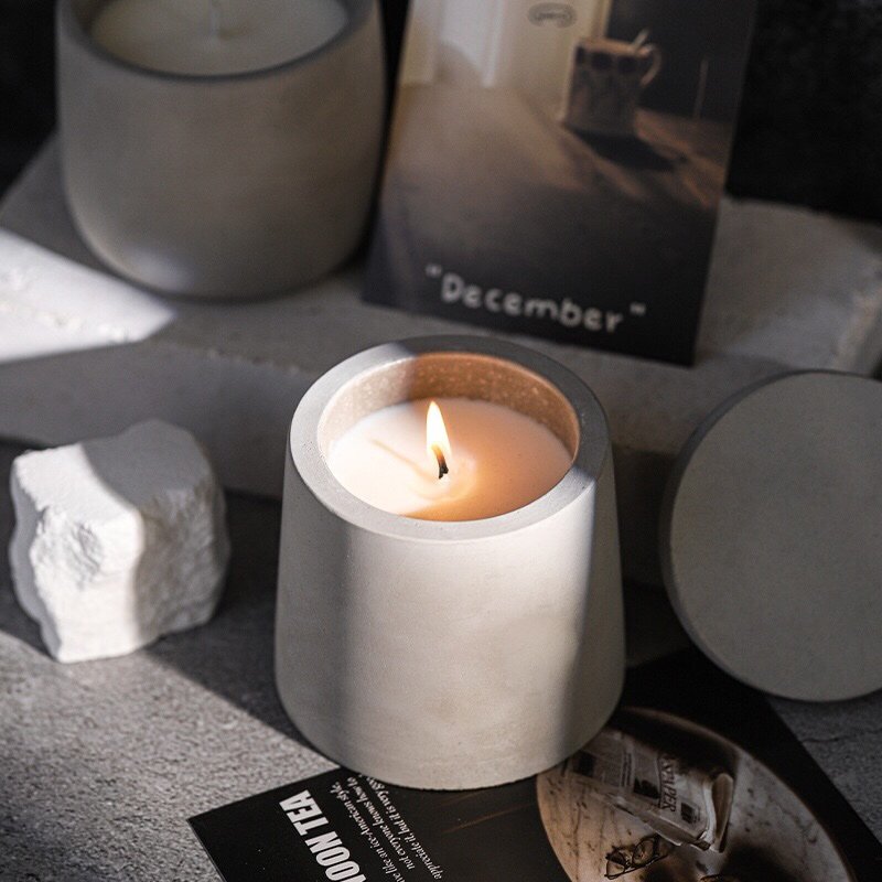 Cement candle cup with the flat lid on, presented in the open white cardboard box.
