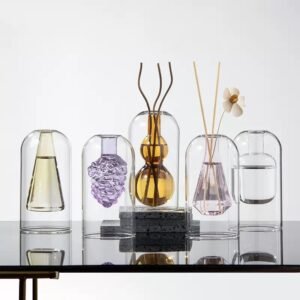 Double layer glass aroma diffuser bottle with adiamond-shaped inner core on a marble surface.