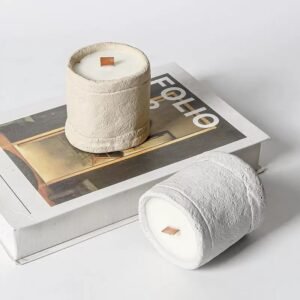 Hand holding a concrete candle jar with a burning candle inside – 125g wax capacity – raw texture and cozy ambiance