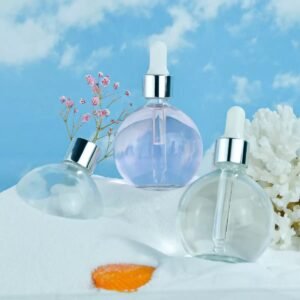 Close-up of clear round essential oil bottle with black cap – droplets forming at tip, precise dispensing detail