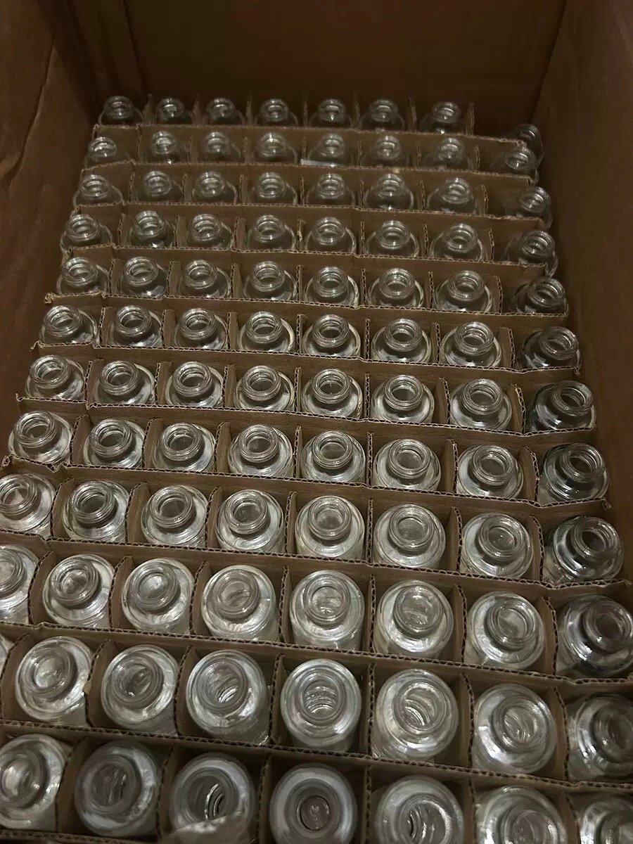 Bulk order of clear perfume bottles packed in egg-crate dividers inside a carton – each bottle separated to prevent breakage during sea freight.