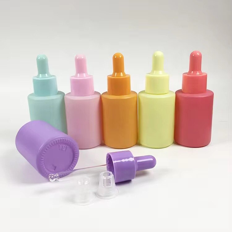 Collection of 30ml solid color dropper bottles in rainbow shades – side view, glossy finish, grouped on a white desk