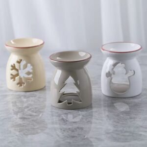 Three Christmas wax melt burners in white (snowman), beige (snowflake), and gray (Christmas tree) – side by side display