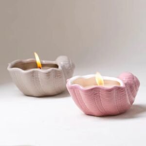 Gray and pink seashell ceramic candle jars with lit candles inside – warm glow, cozy ambiance, coastal decor