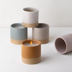 Five two-tone rough glaze ceramic candle jars stacked in a pyramid, some with lit candles – grey-yellow, orange-yellow, pink-yellow finishes
