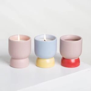 Three ceramic candle jars side by side – solid pink, blue-yellow, pink-red – wine-glass silhouette, color comparison