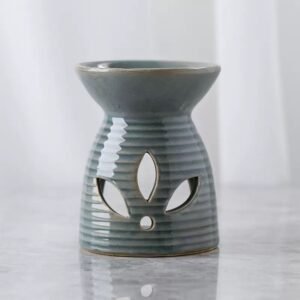 Lotus cutout ceramic wax burner in cyan – close-up of carved petal pattern, soft candle glow through openings