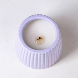 Top-down view of purple ceramic jar with burning candle – wax pool, relief pattern visible around rim